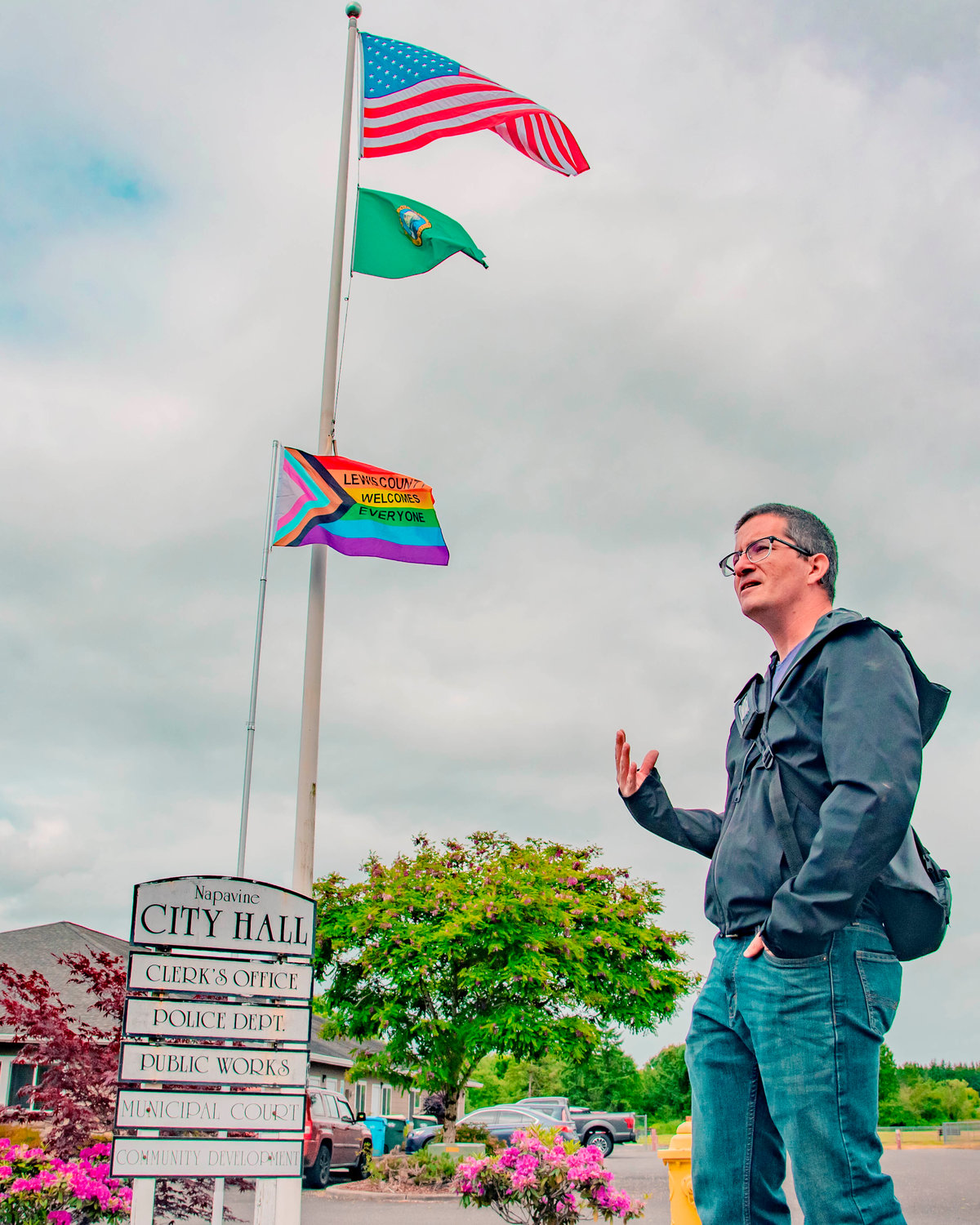 Kyle Wheeler of the Lewis County Lollipop Guild talks about why they wear a body cam after a flag which reads, “Lewis County Welcomes Everyone,” was erected outside Napavine City Hall Thursday morning.